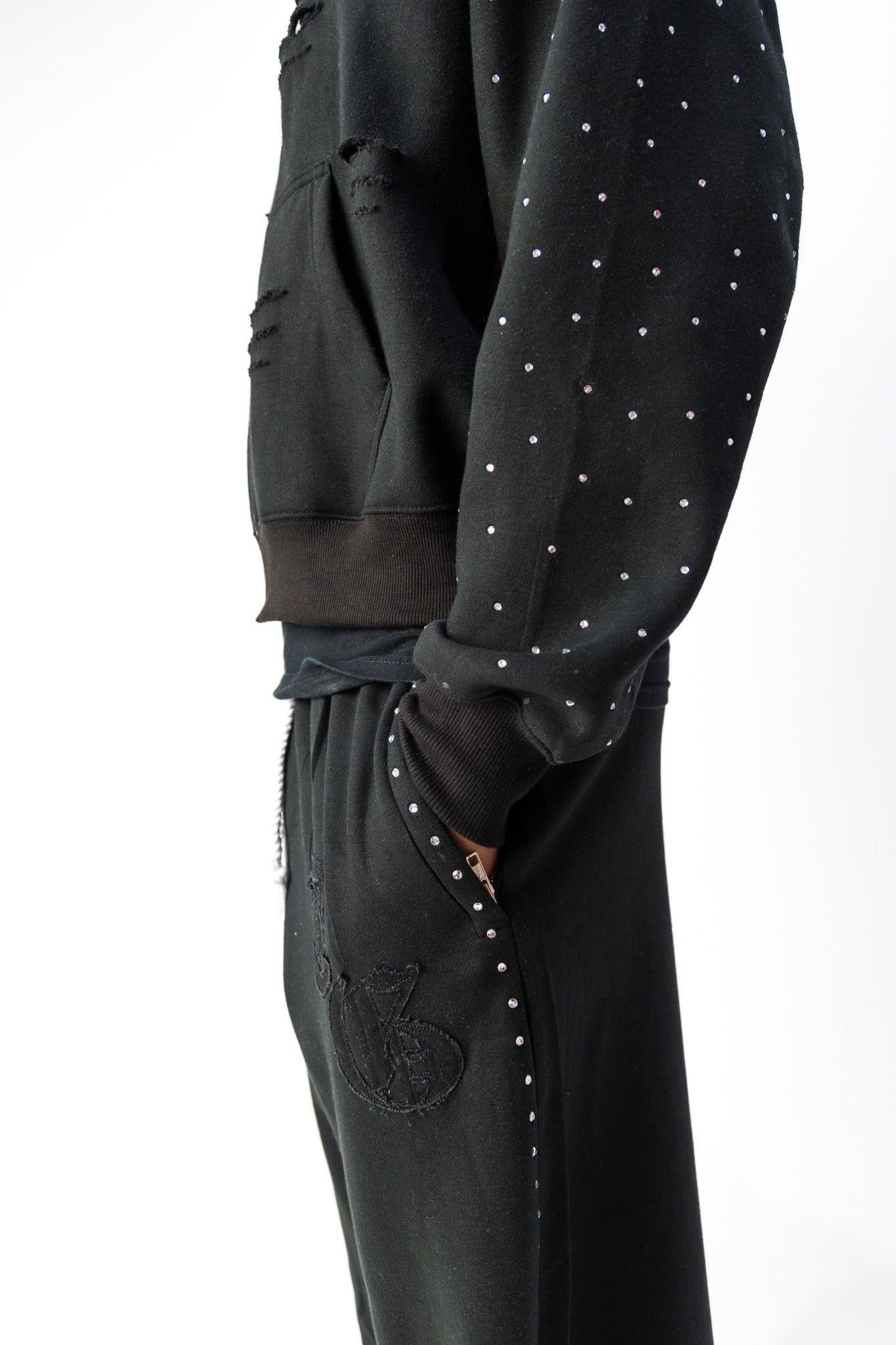 Black detail view of TG Rhinestone oversized, distressed rhinestone sweatpants. 