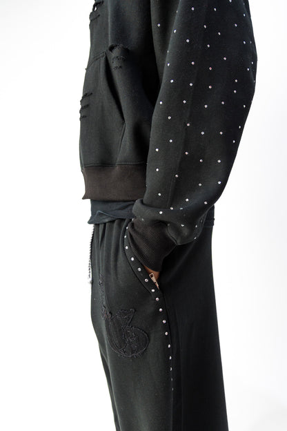 Black detail view of TG Rhinestone oversized, distressed rhinestone sweatpants. 